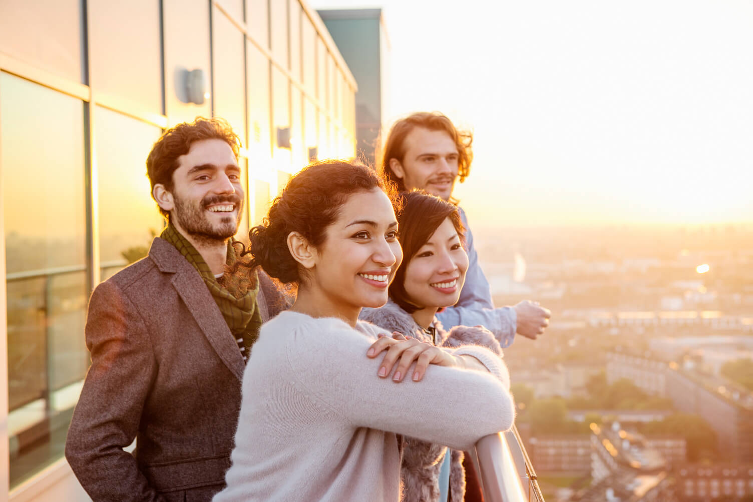 A group of four people looking at the horizon from their office balcony